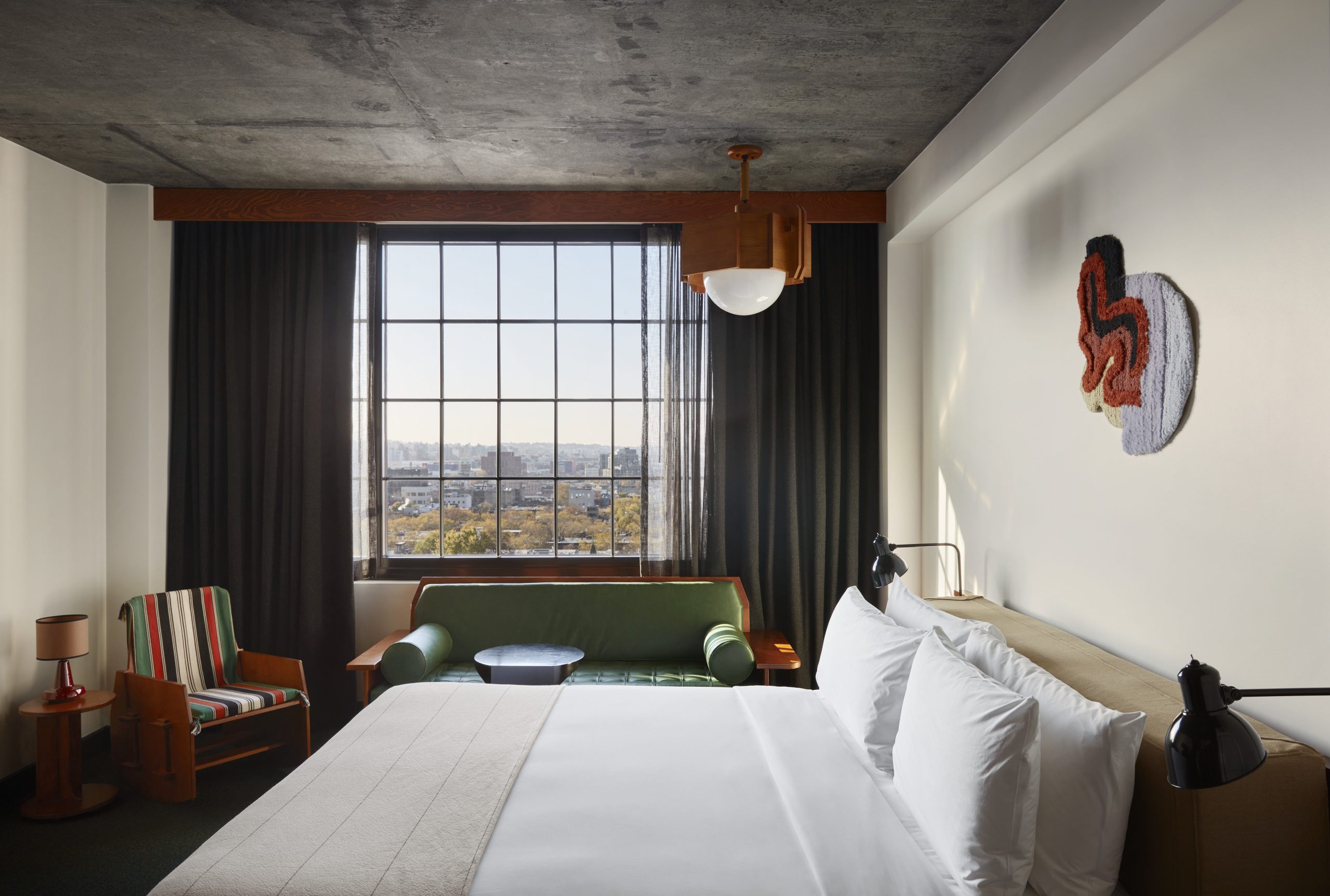 A room with green sofa, striped chair and city views featuring a park and greenery