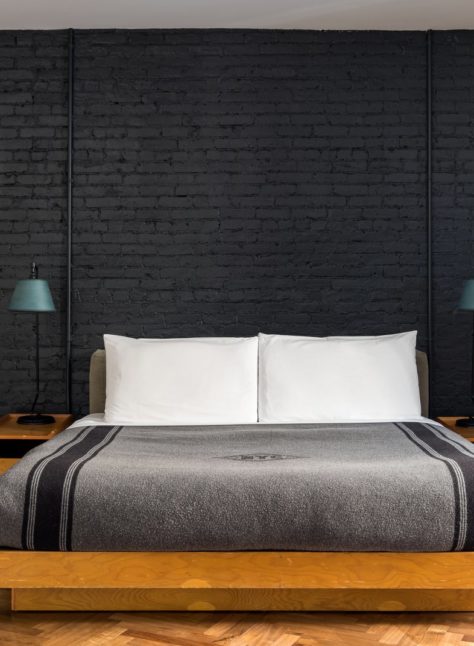 A black exposed brick wall is juxtaposed with bight, polished wooden flooring