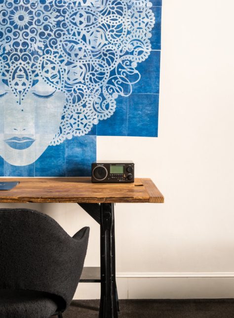 A vintage wooden desk provides space to work and is juxtaposed with the modern vibe of the room