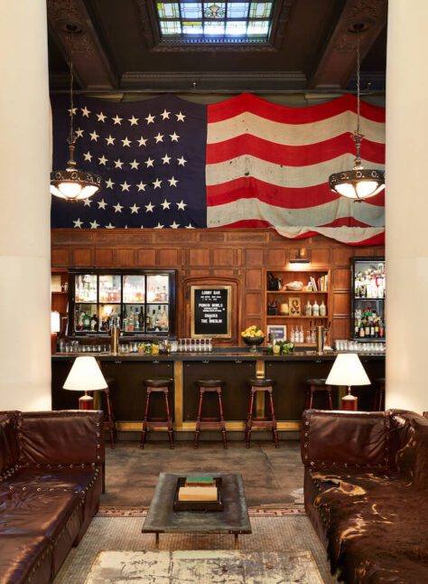 a lobby with mosaic tile featuring a large American flag framed by two white floor to ceiling pillars