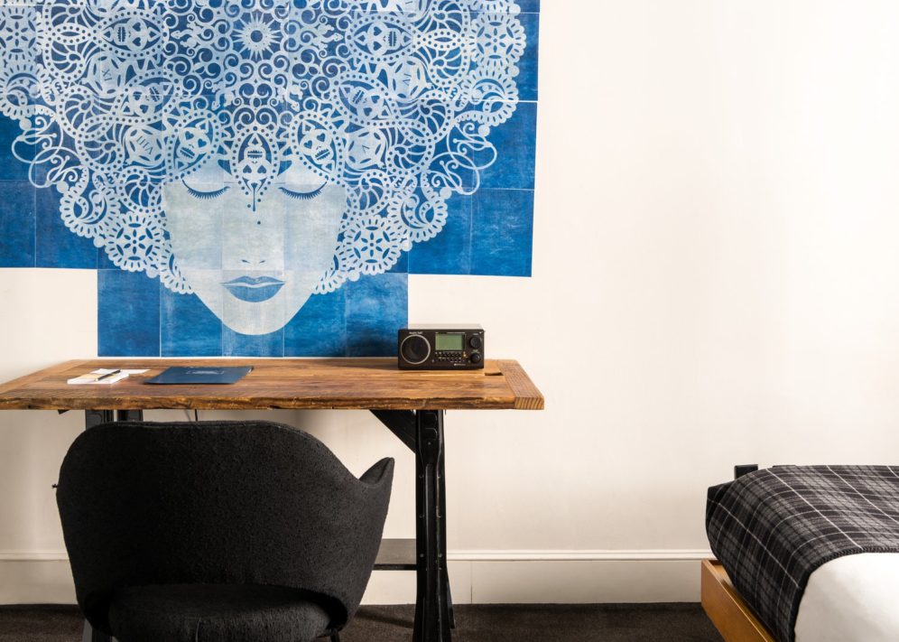 A vintage wooden desk provides space to work and is juxtaposed with the modern vibe of the room