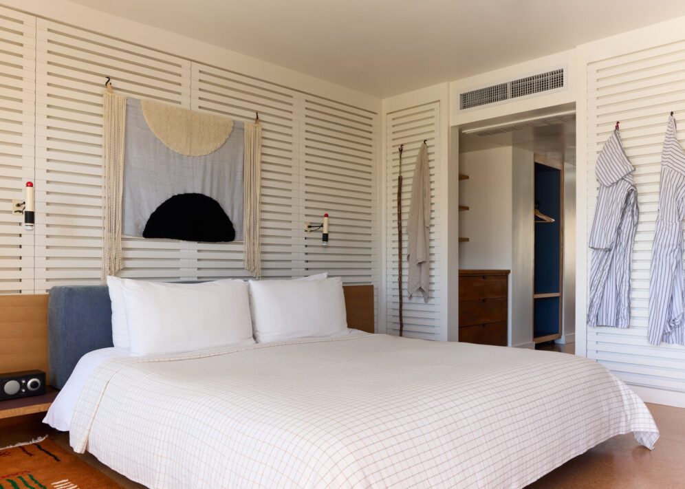 A private bedroom has robes adorning the wall and wall lamps for light into the night