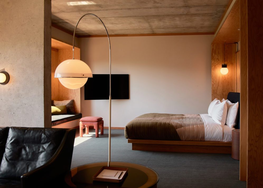 Modern furnishings adorn a living room looking into a bedroom; natural light floods the room