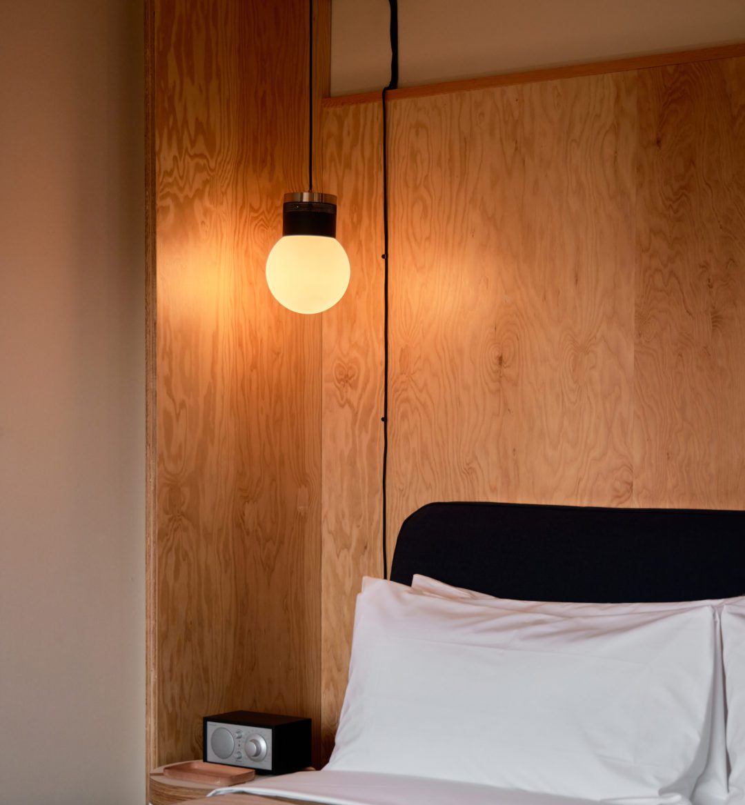 A modern globe light sits above a bed
