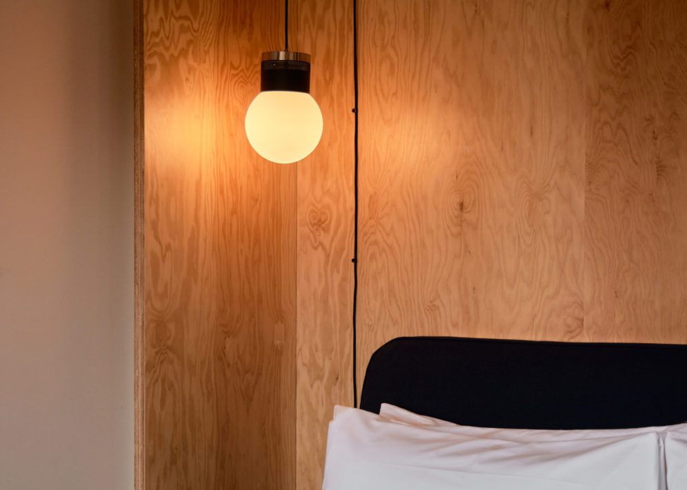 A modern globe light sits above a bed