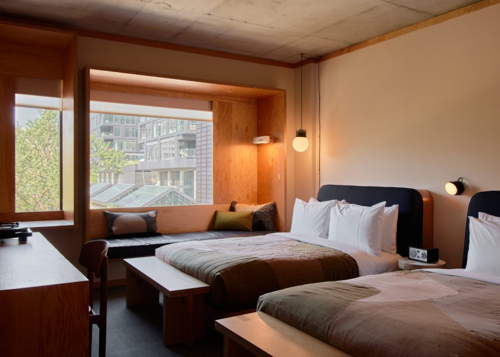 A black leather seating area is next to two bed; plush cushions provide added comfort