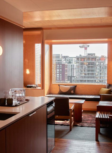 A sink with dishwasher opens up to a large living room with windows and natural light